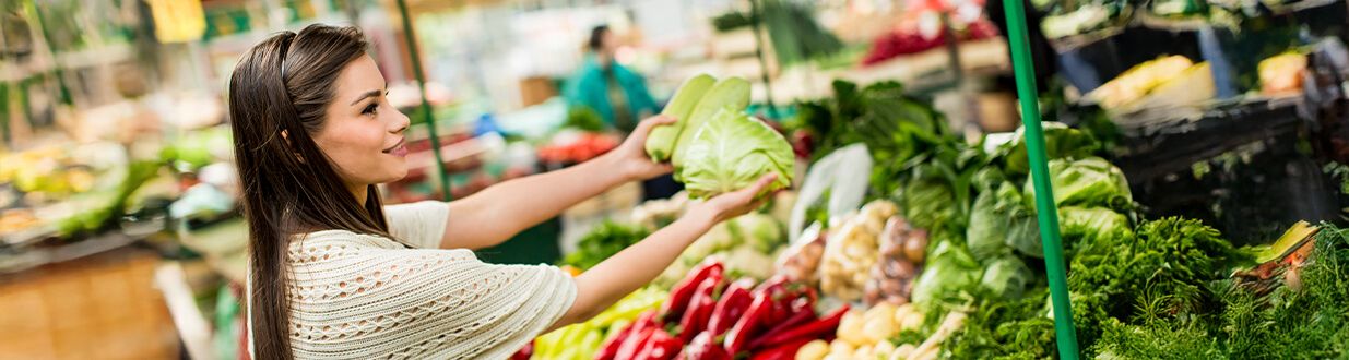 a woman holding up garlic at the farmers market where-is-the-captiva-farmers-market-located